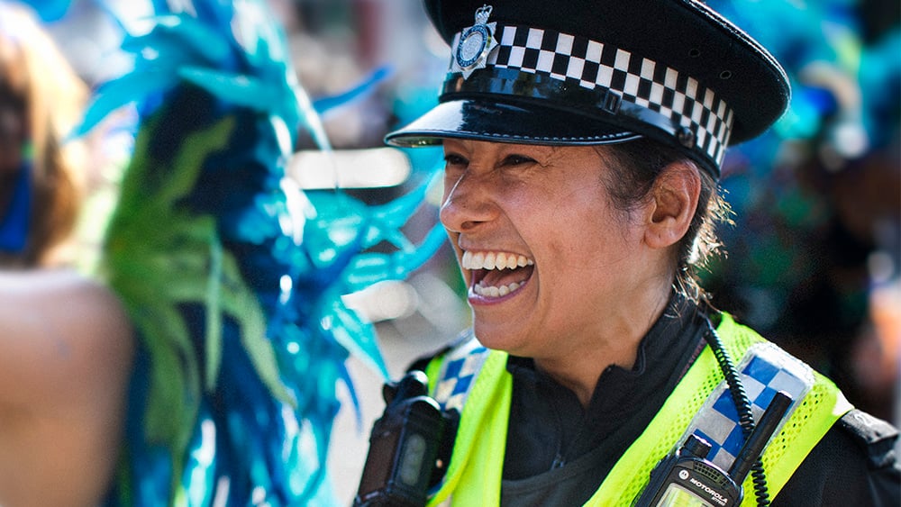 Female police officer laughing with carnival go-er.