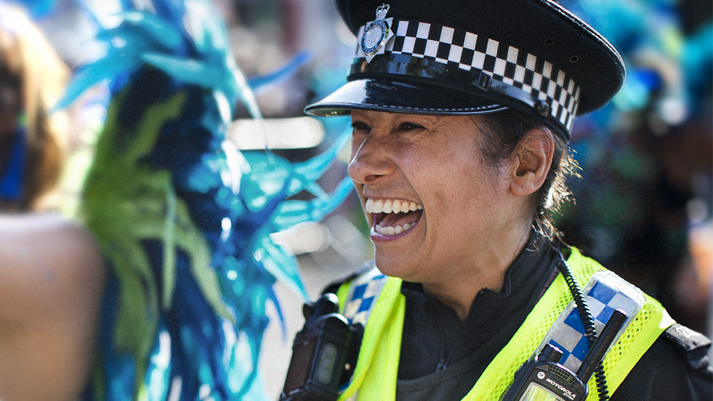 Female police officer laughing with carnival go-er.