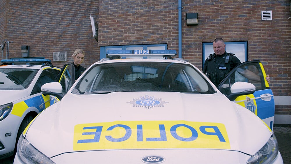 Two officers getting into a police car.