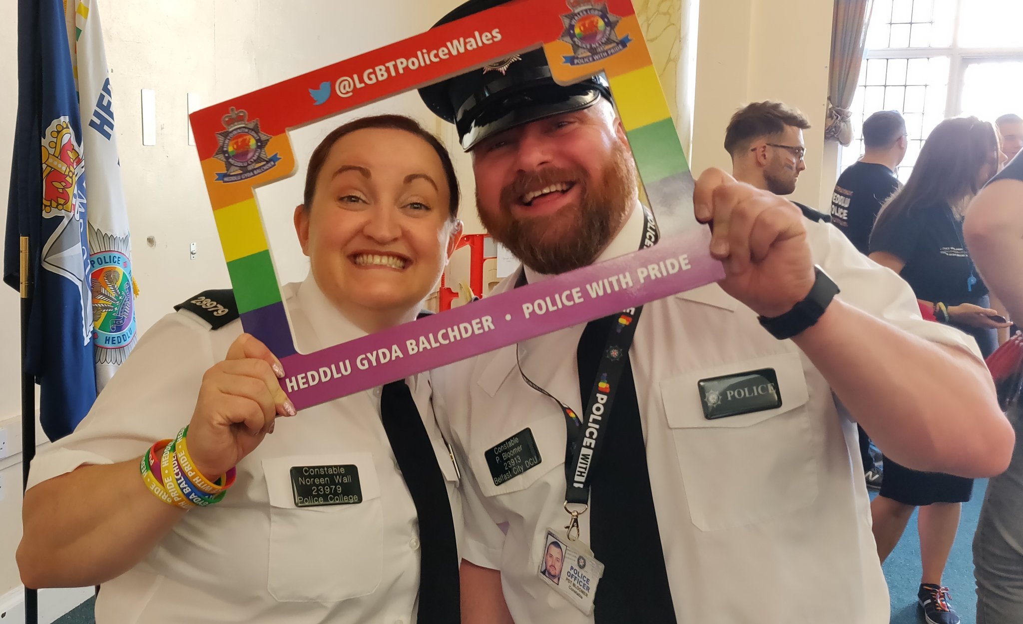 Officers smiling to camera through Pride picture frame.