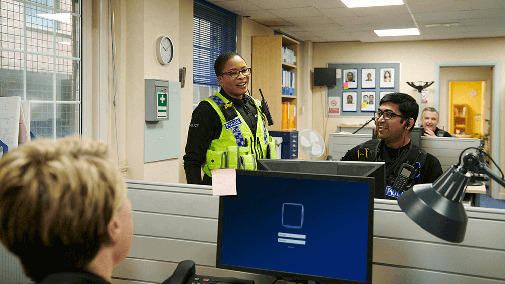 Three officers talking in a control room. 