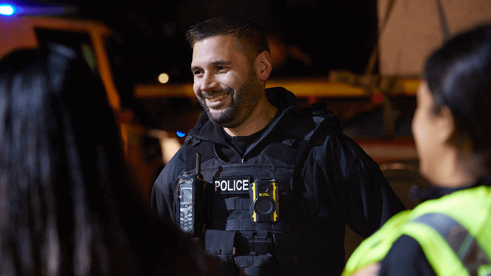 Male officer chatting to two female officers at night on the street. 