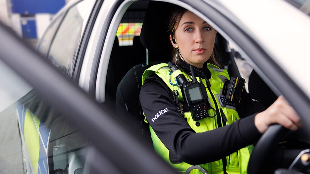 Female officer sitting in the driving seat of a police car.