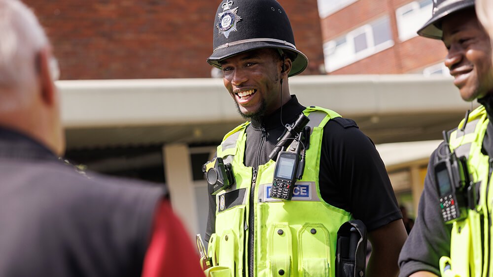 Female officer smiling with cityscape in background.